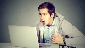 shocked man with laptop computer sitting at table