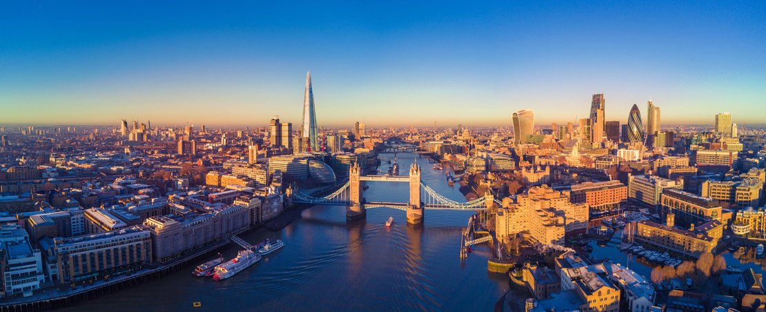 Aerial view of the London skyline at sunset, showcasing iconic buildings silhouetted against a colorful sky.
