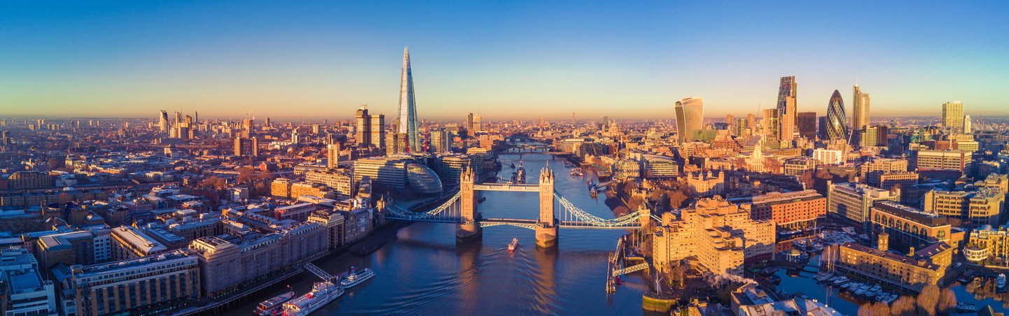 Aerial view of the London skyline at sunset, showcasing iconic buildings silhouetted against a colorful sky.