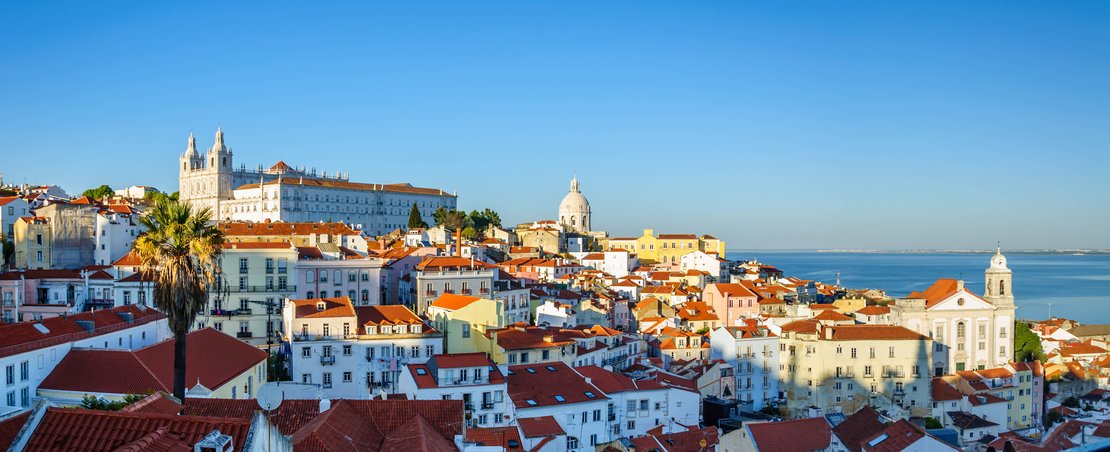 A panoramic view of Lisbon, Portugal, showcasing its iconic architecture and vibrant cityscape under a clear blue sky.