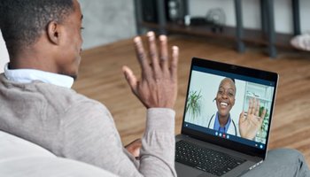Male african patient on conference video call with female online doctor.
