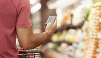 Close Up Of Man Reading Shopping List From Mobile Phone In Supermarket
