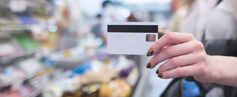 Hand with a white credit card on the background of a supermarket