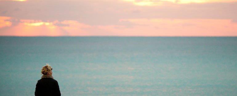 person look out over sea and sunset