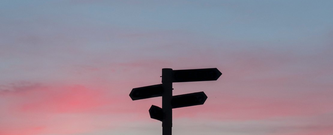Signpost against sunset