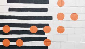 photo: orange dots over black stripes on white brick wall