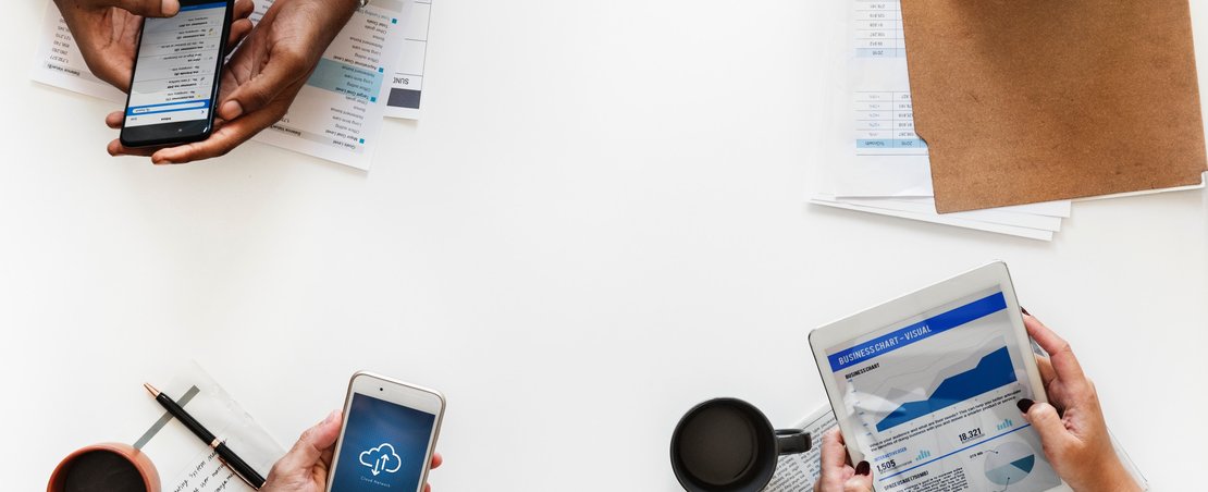 People holding devices and paper showing graphs and uploading - only hands/devices in shot