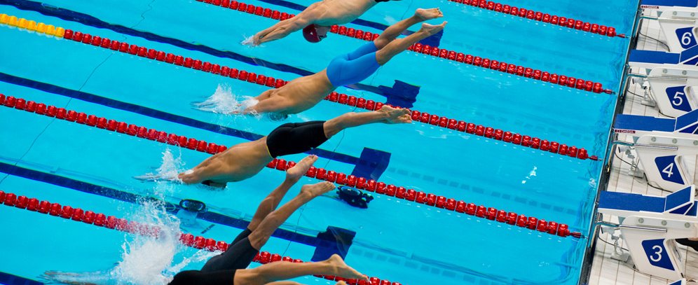 Swimmers diving into swimming pool