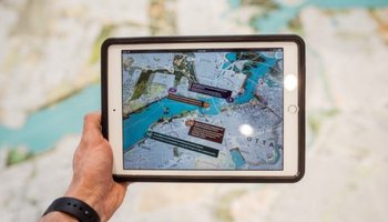 Person holding iPad with city plans over map