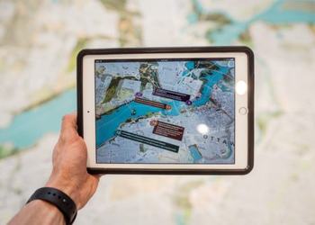 Person holding iPad with city plans over map
